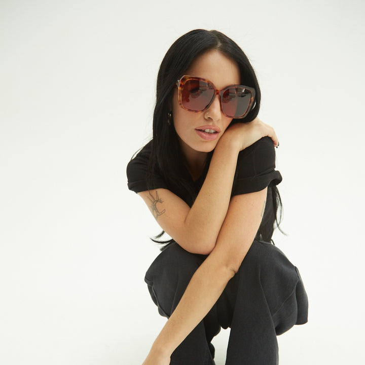 Lali wearing sunglasses and a black outfit on a white background