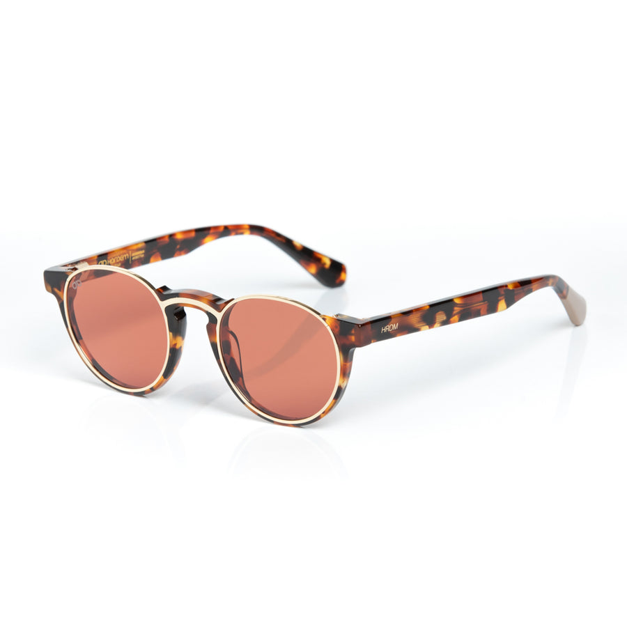 Sunglasses with tortoiseshell frame and rose gold lenses on a white background