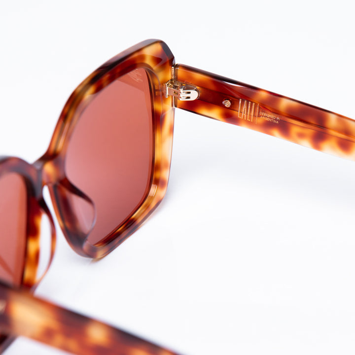 Tortoiseshell sunglasses with brown lenses on a white background