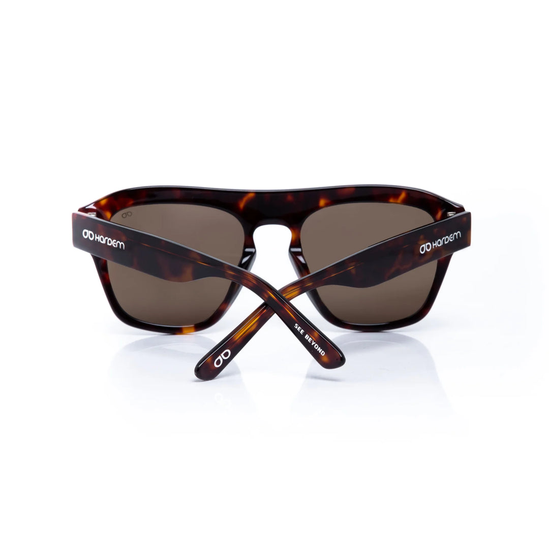 Crossed sunglasses with tortoiseshell frame and dark lenses on a white background