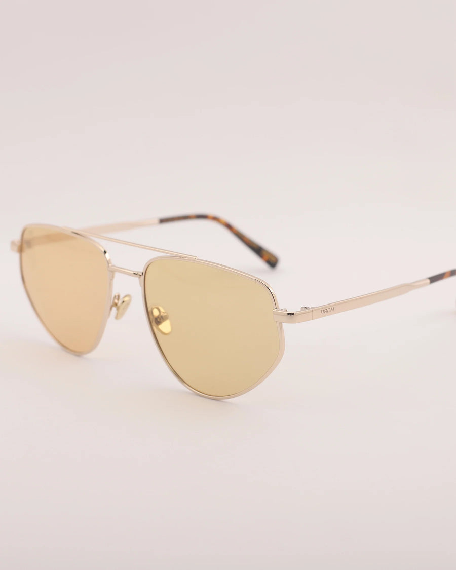 Gold sunglasses on a light beige background