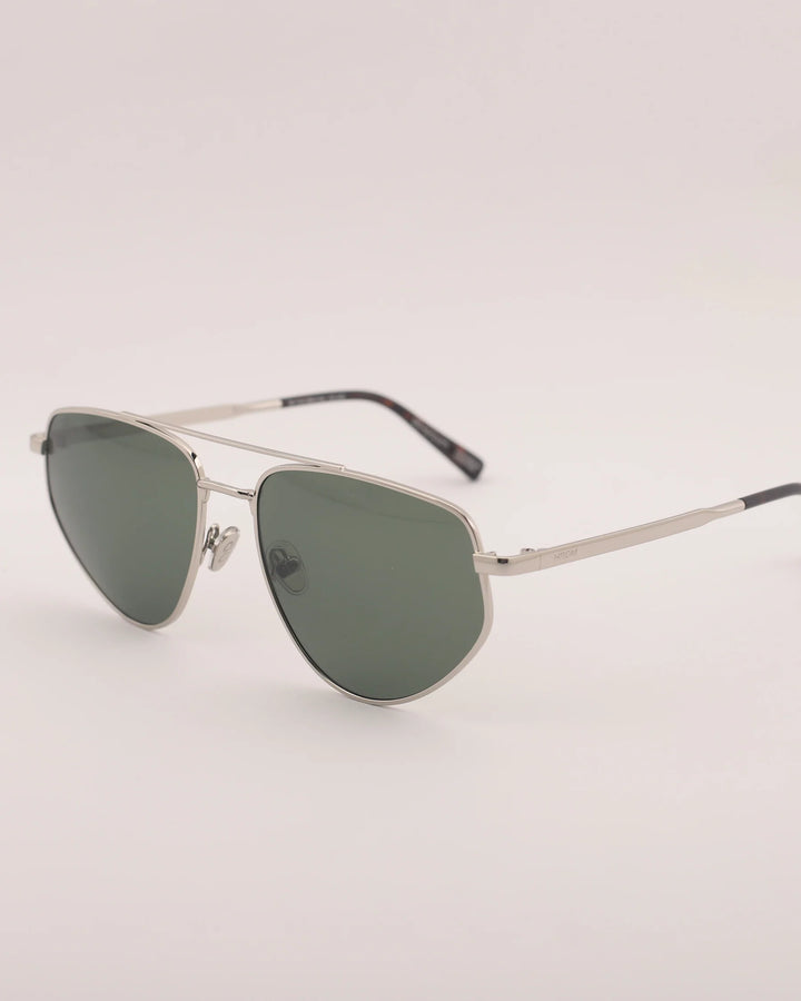 Sunglasses with metallic frame and green lenses on a light gray background