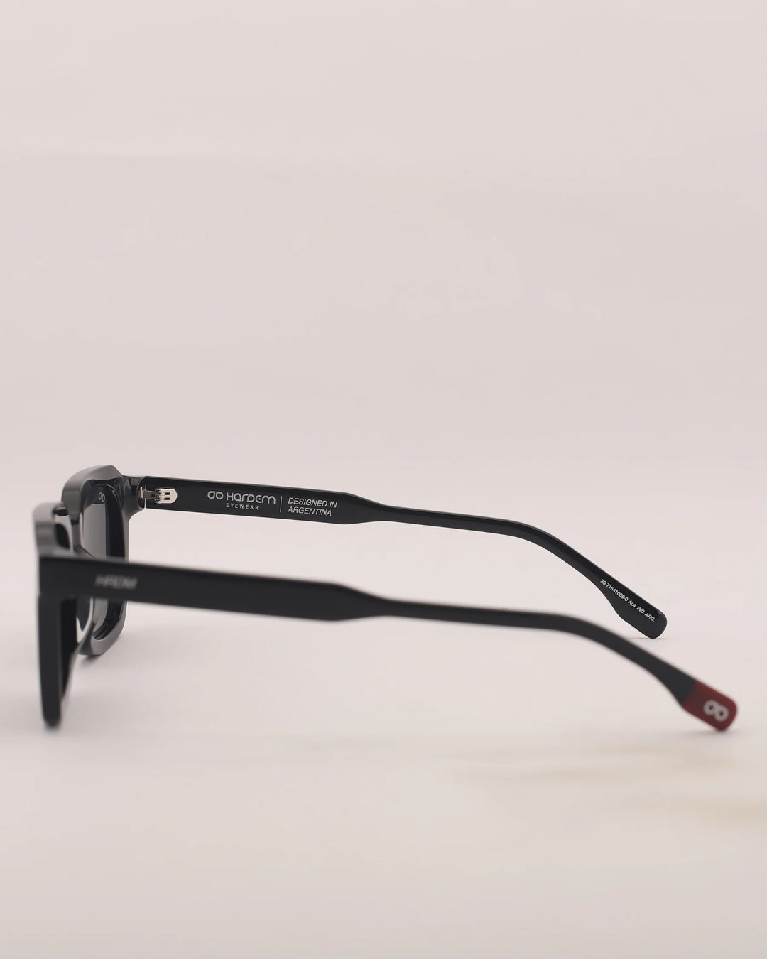 Black sunglasses with a brand logo on the frame against a light gray background