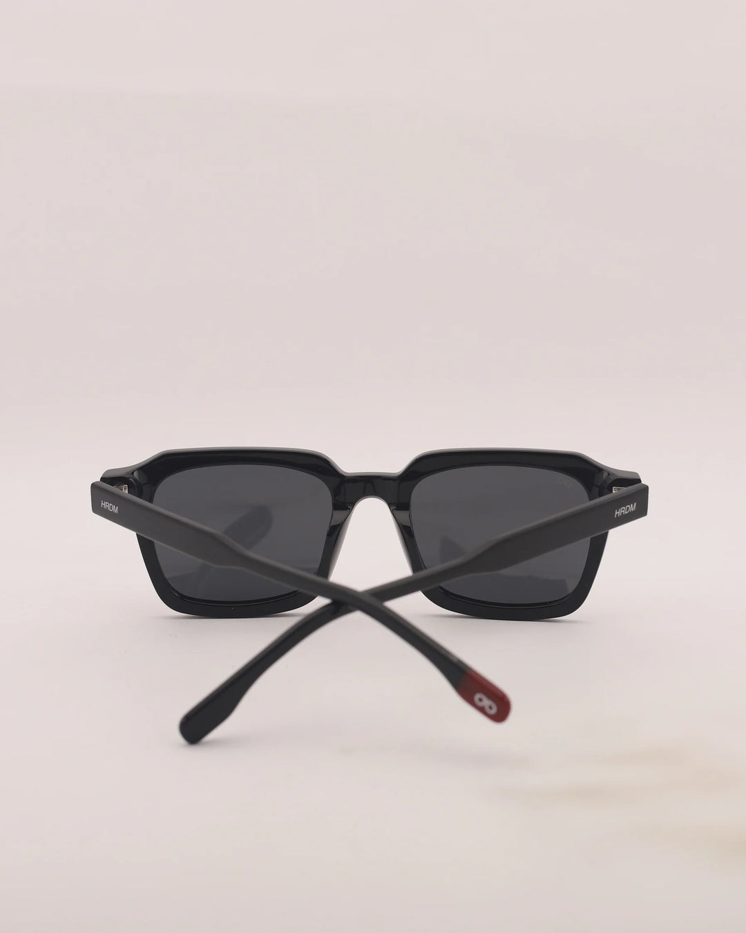 Black sunglasses with a red accent on a light gray background