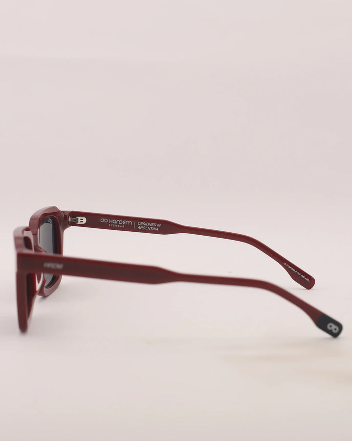 Red sunglasses with a brand logo on a light gray background