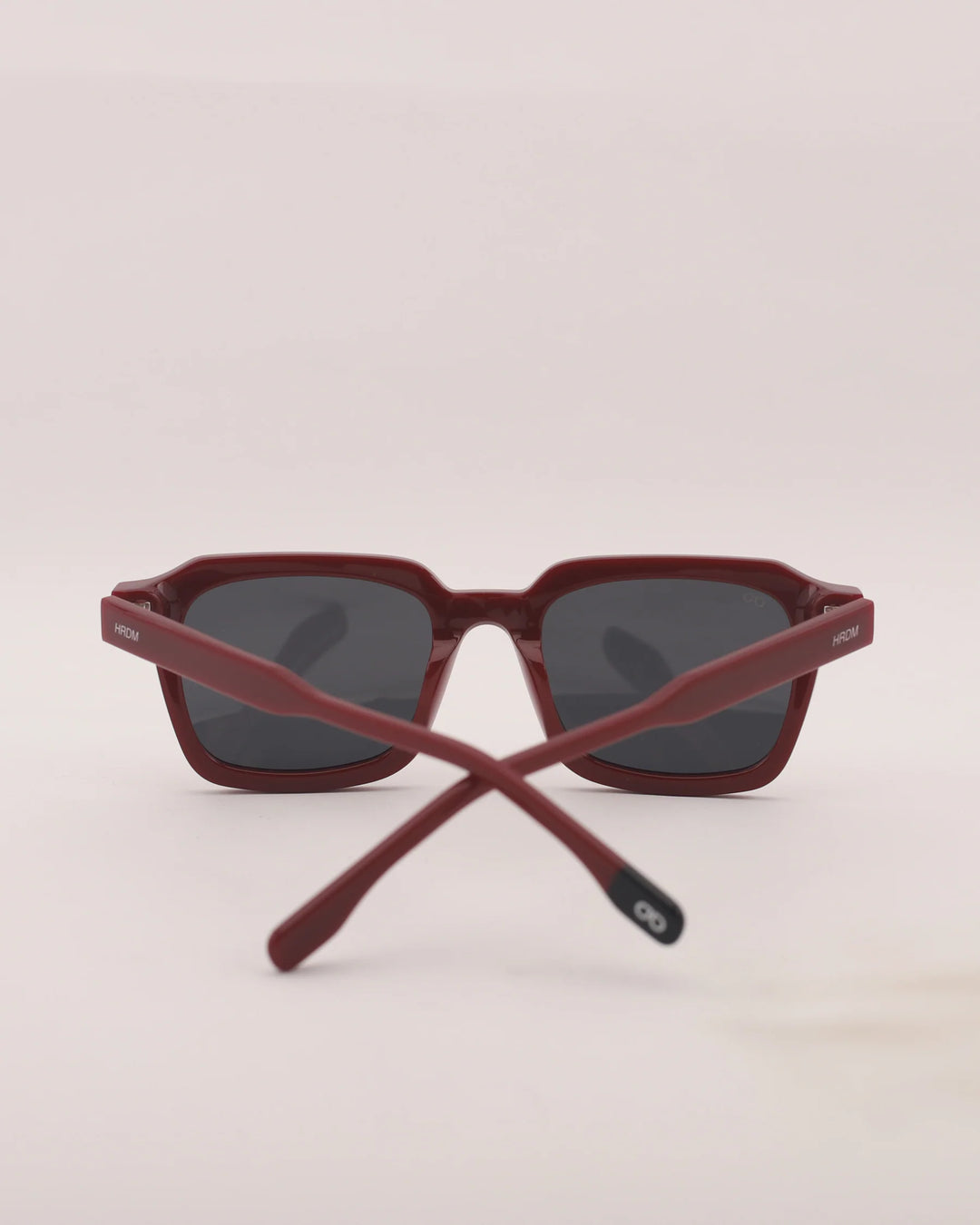 Crossed red sunglasses on a light beige background