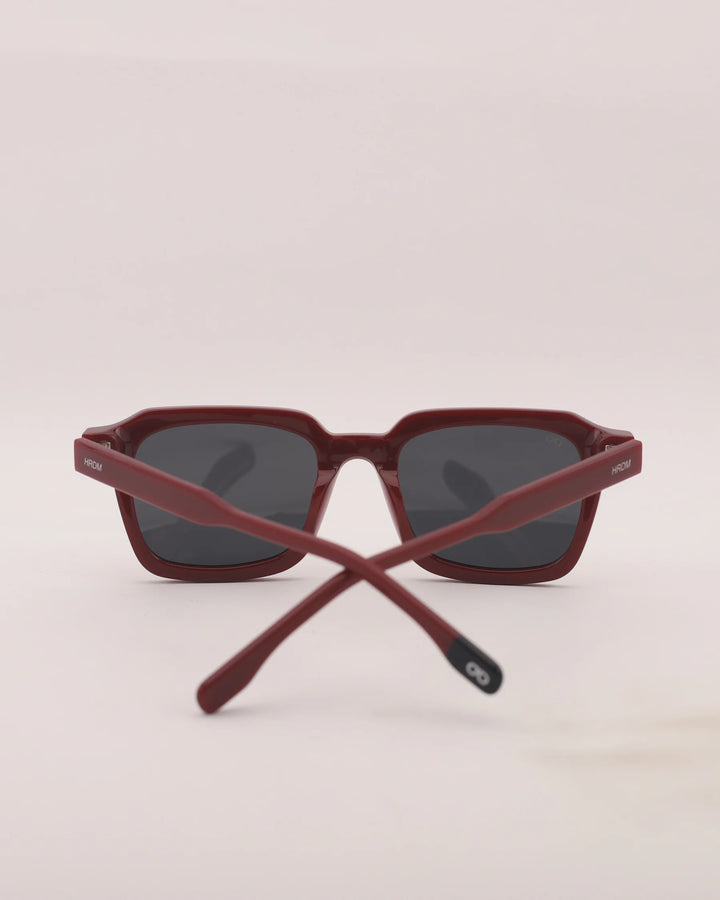 Crossed red sunglasses on a light beige background