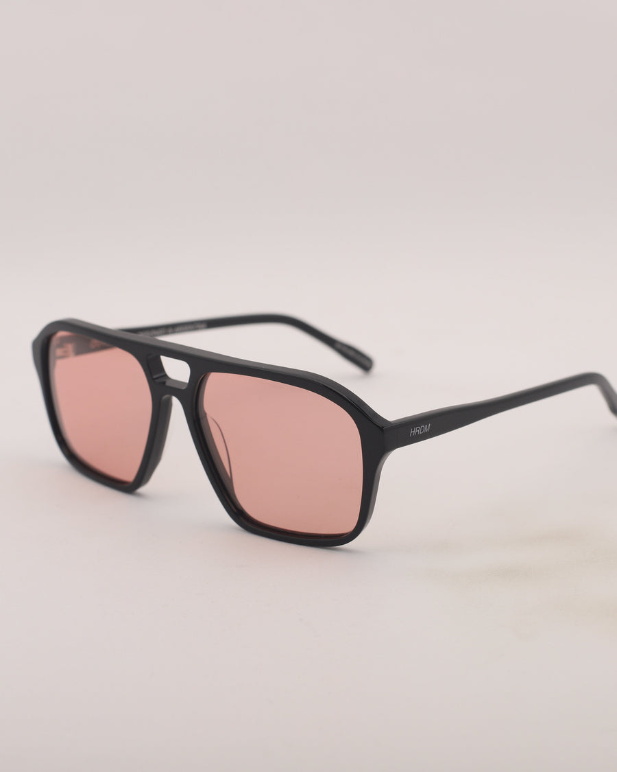 Black sunglasses with pink lenses on a light gray background