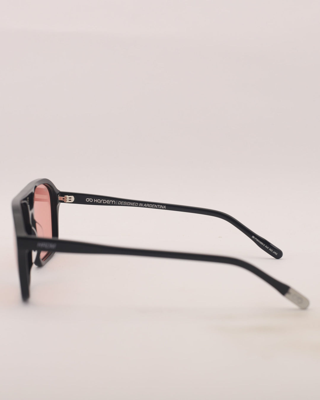 Black sunglasses with pink lenses on a light gray background
