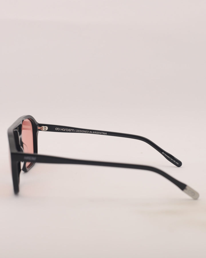 Black sunglasses with pink lenses on a light gray background