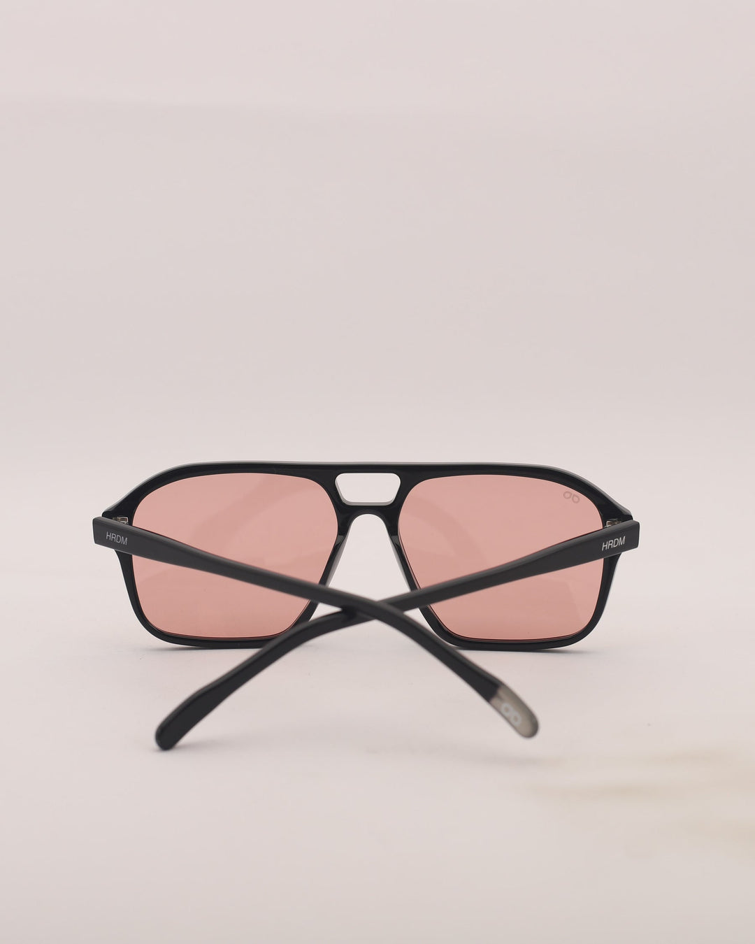 Sunglasses with black frame and pink lenses on a light gray background