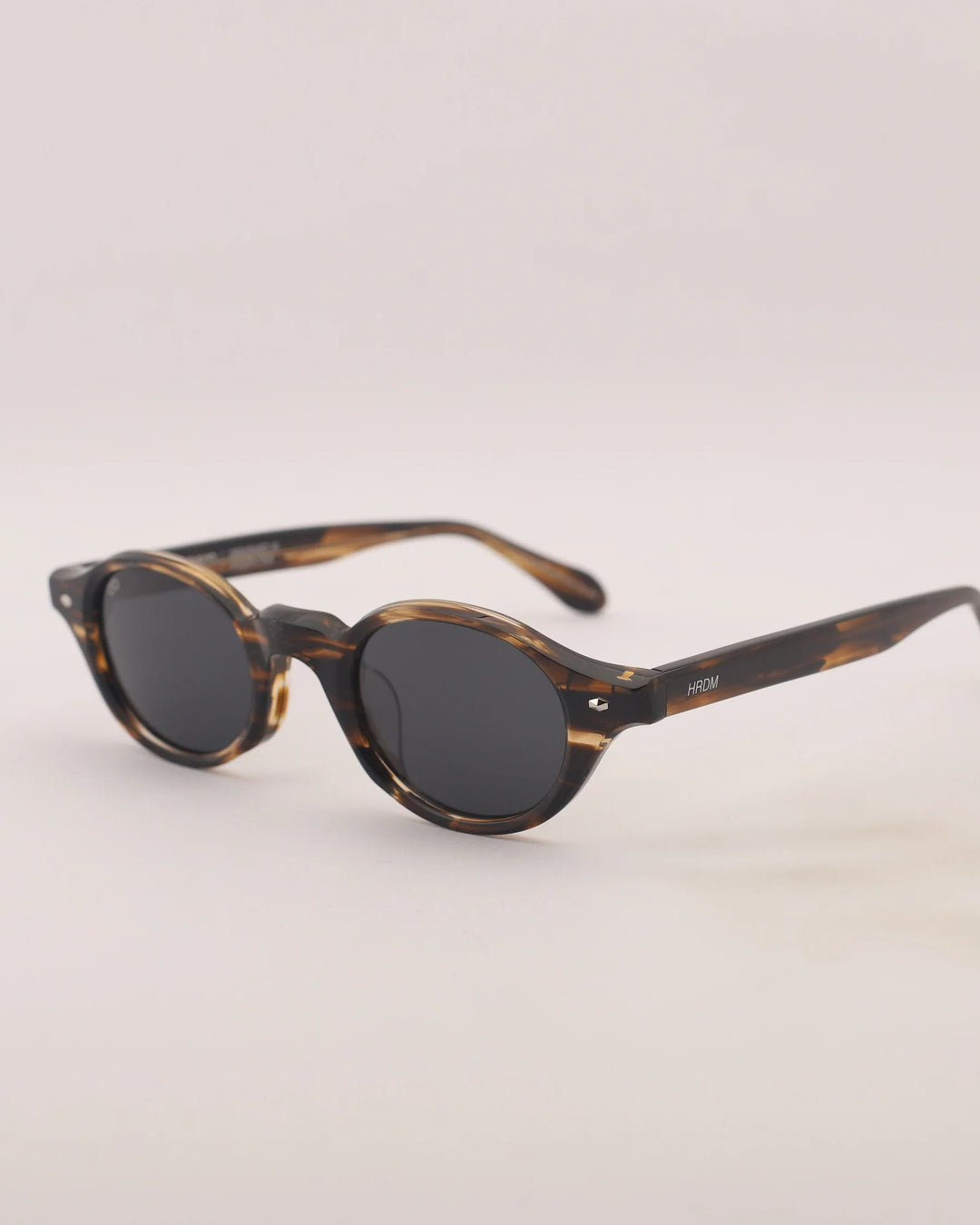 Round sunglasses with tortoiseshell frame on a light gray background