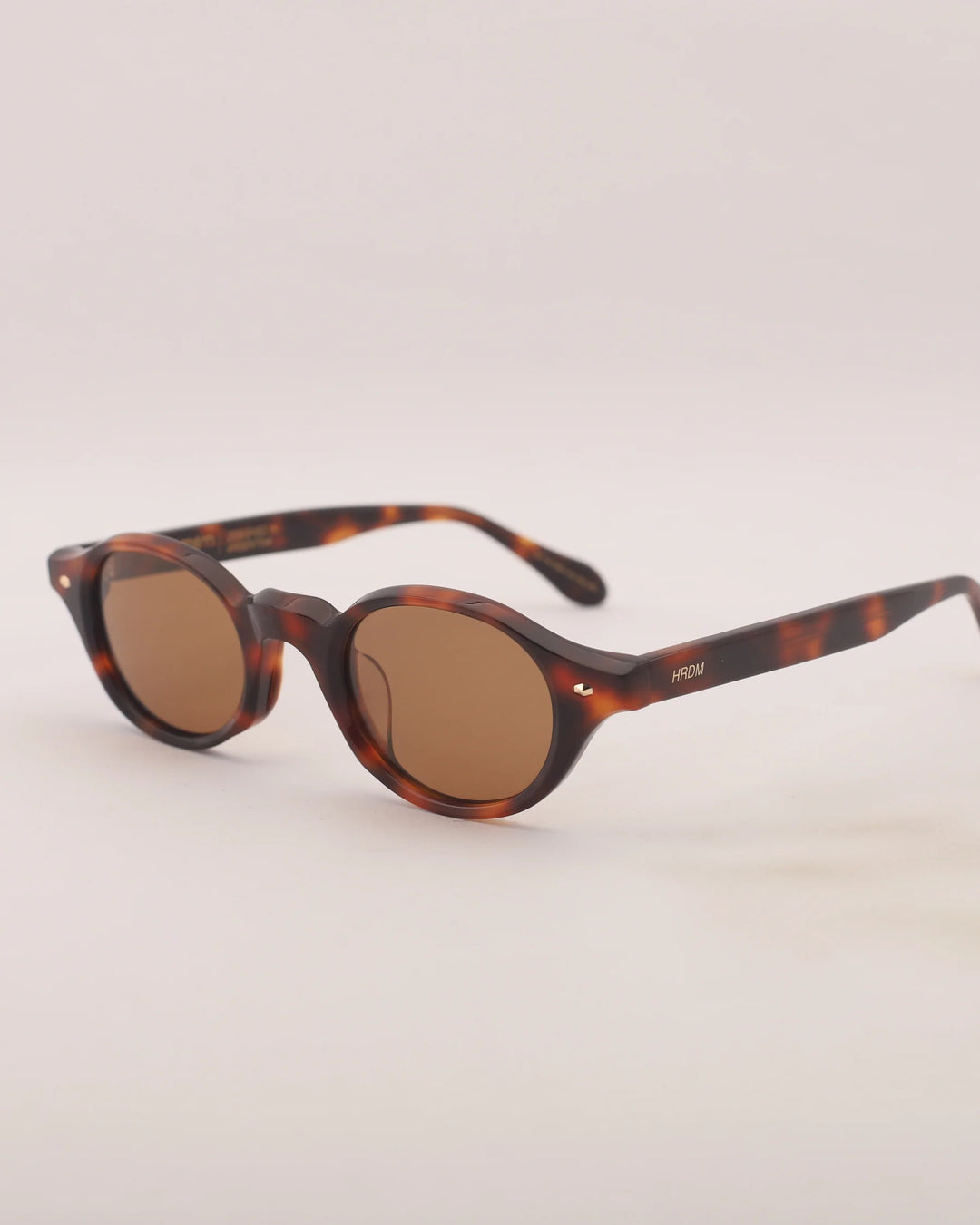 Sunglasses with tortoiseshell frame and brown lenses on a light gray background
