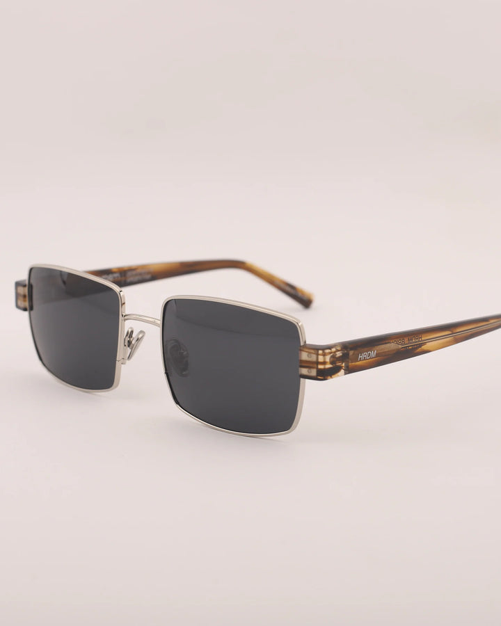 Sunglasses with tortoiseshell frame and dark lenses on a light gray background