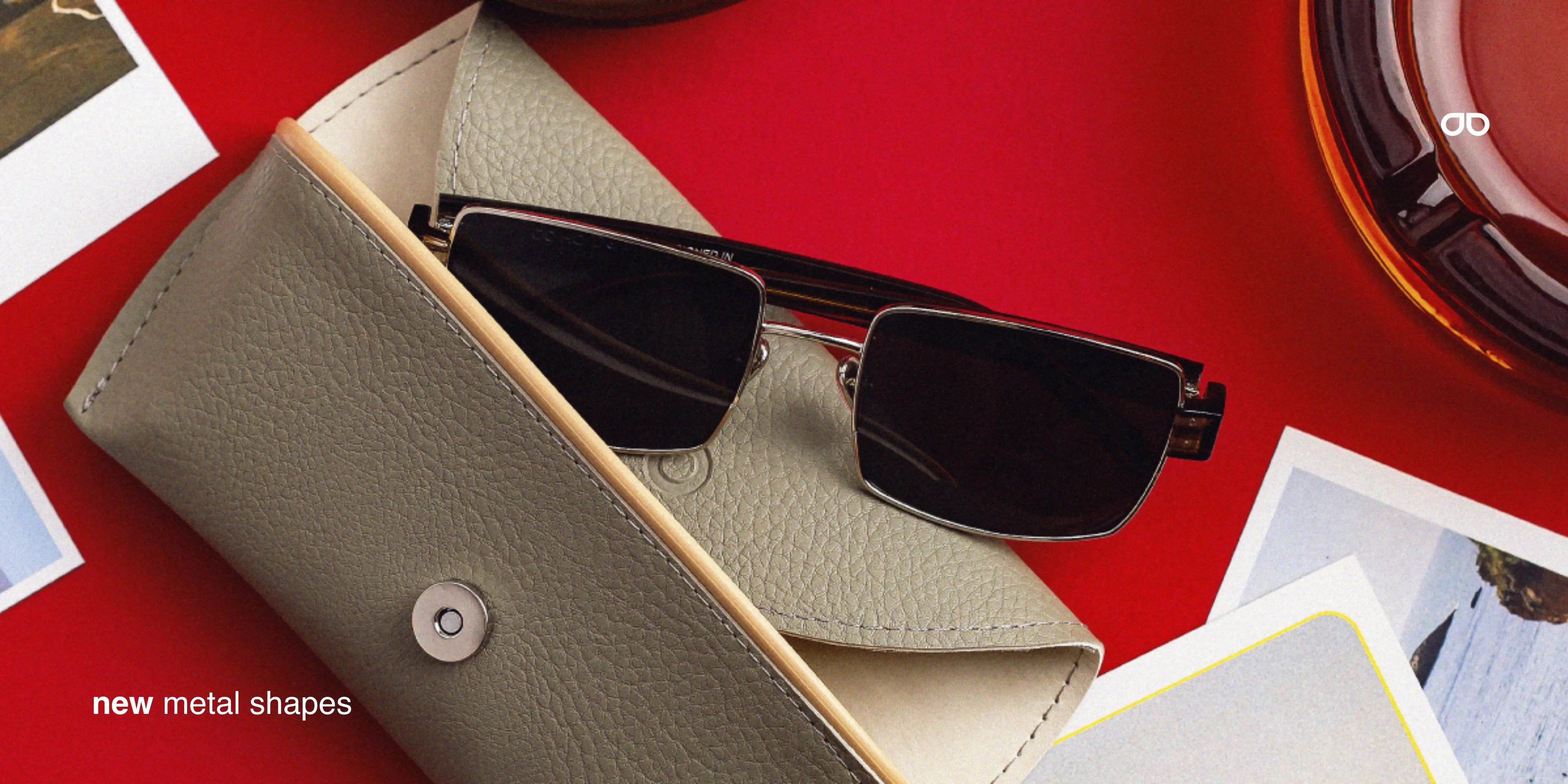 Sunglasses in a beige case on a red surface with text 'new metal shapes'.