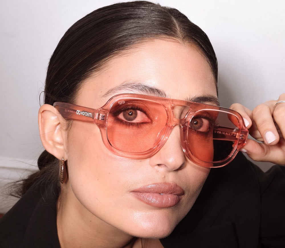 Person wearing pink sunglasses with a neutral background