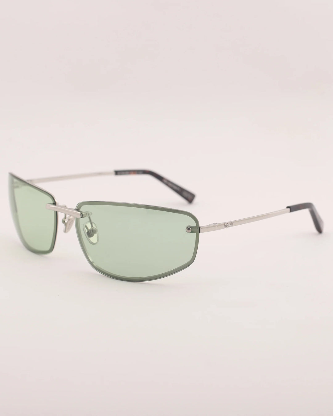 Sunglasses with green lenses and thin metal frame on a light gray background