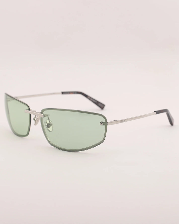 Sunglasses with green lenses and thin metal frame on a light gray background