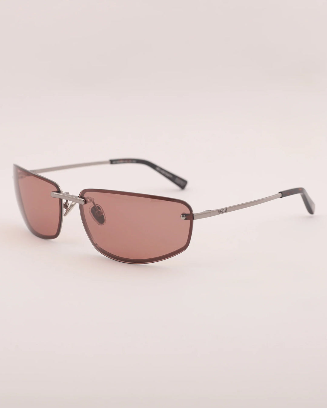 Sunglasses with brown lenses and thin metal frame on a light beige background