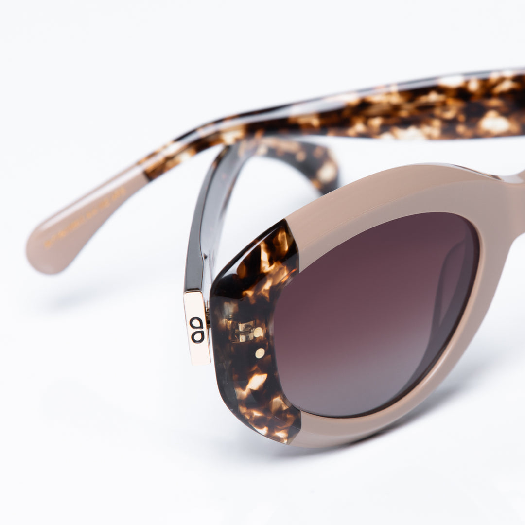 Sunglasses with tortoiseshell frame and dark lenses on a light gray background