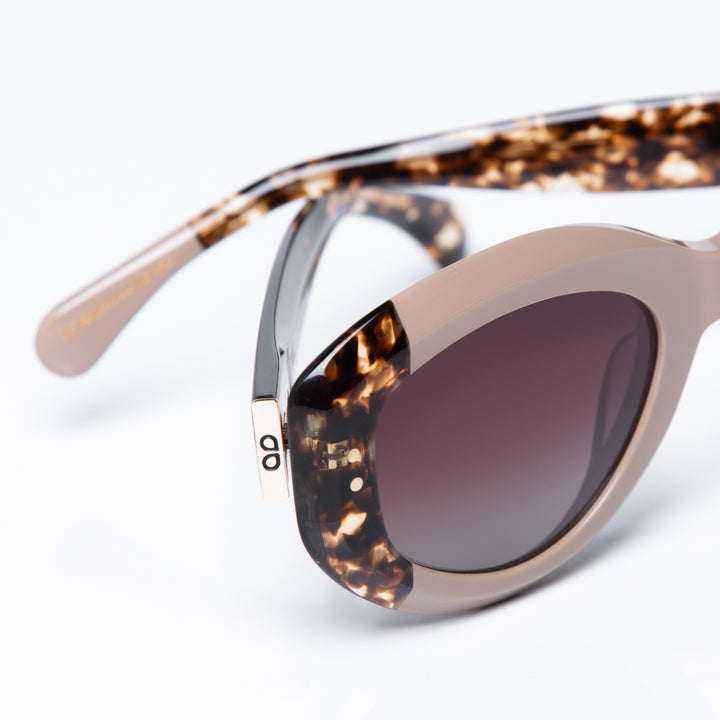 Sunglasses with tortoiseshell frame and dark lenses on a light gray background