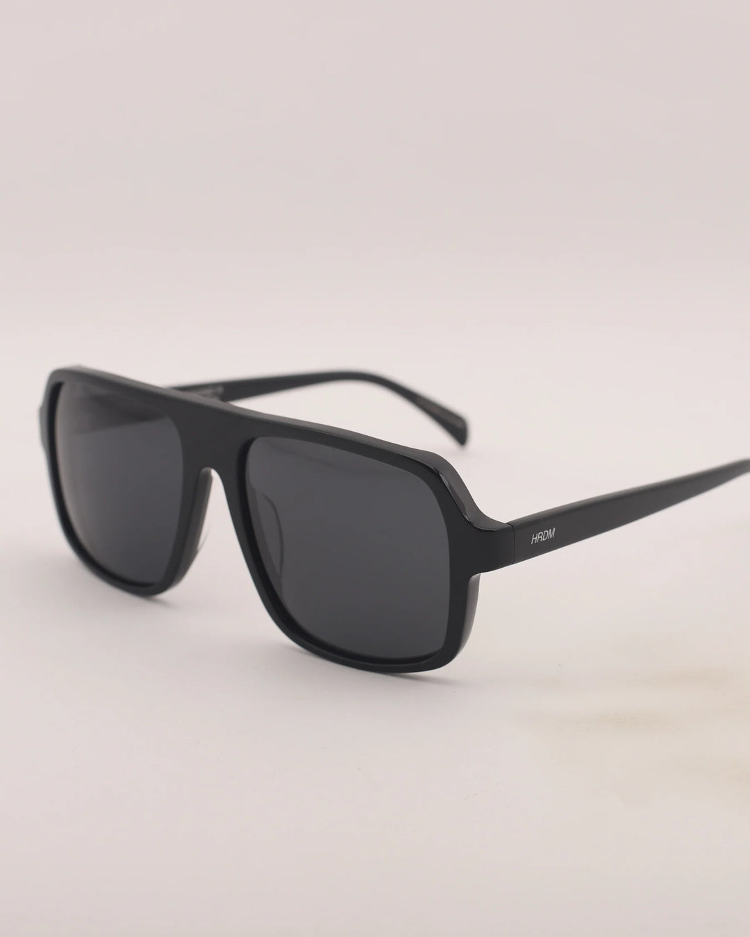 Black sunglasses with a gray lens on a light gray background