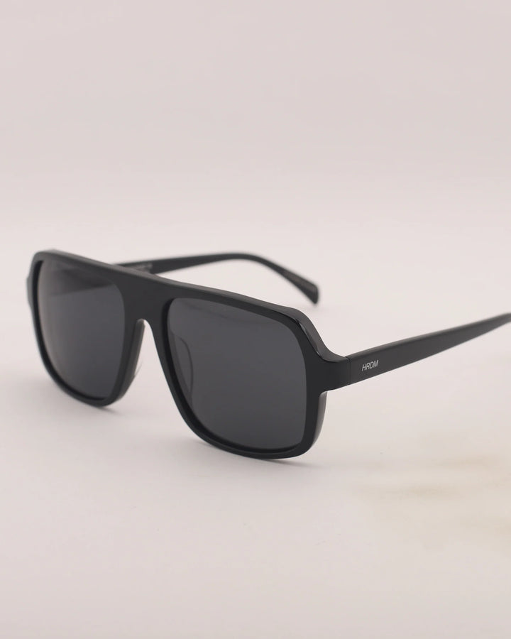 Black sunglasses with a gray lens on a light gray background