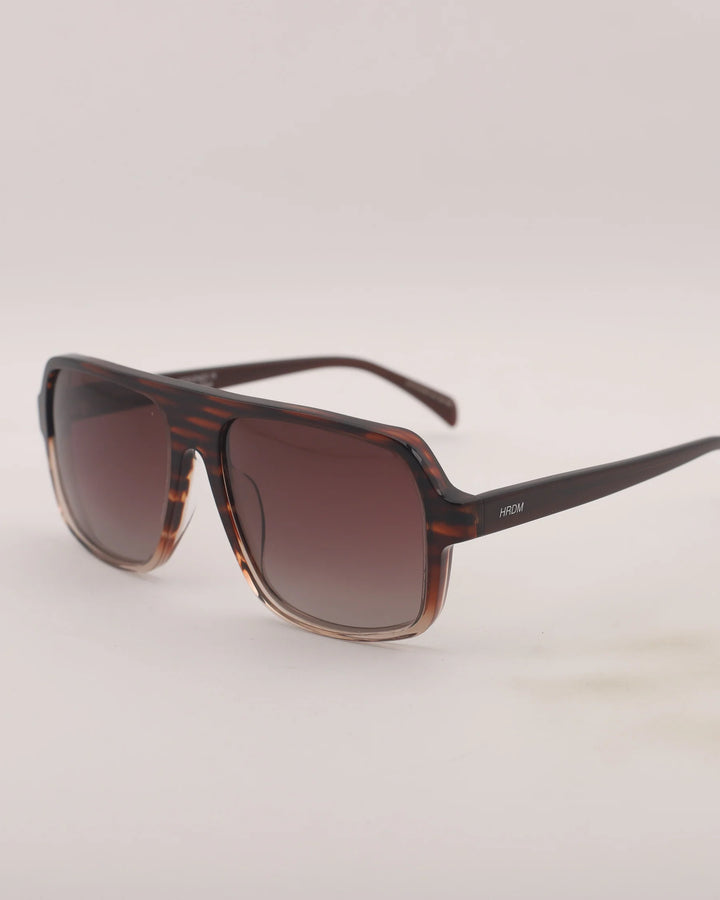 Sunglasses with a tortoiseshell frame and brown lenses on a light gray background