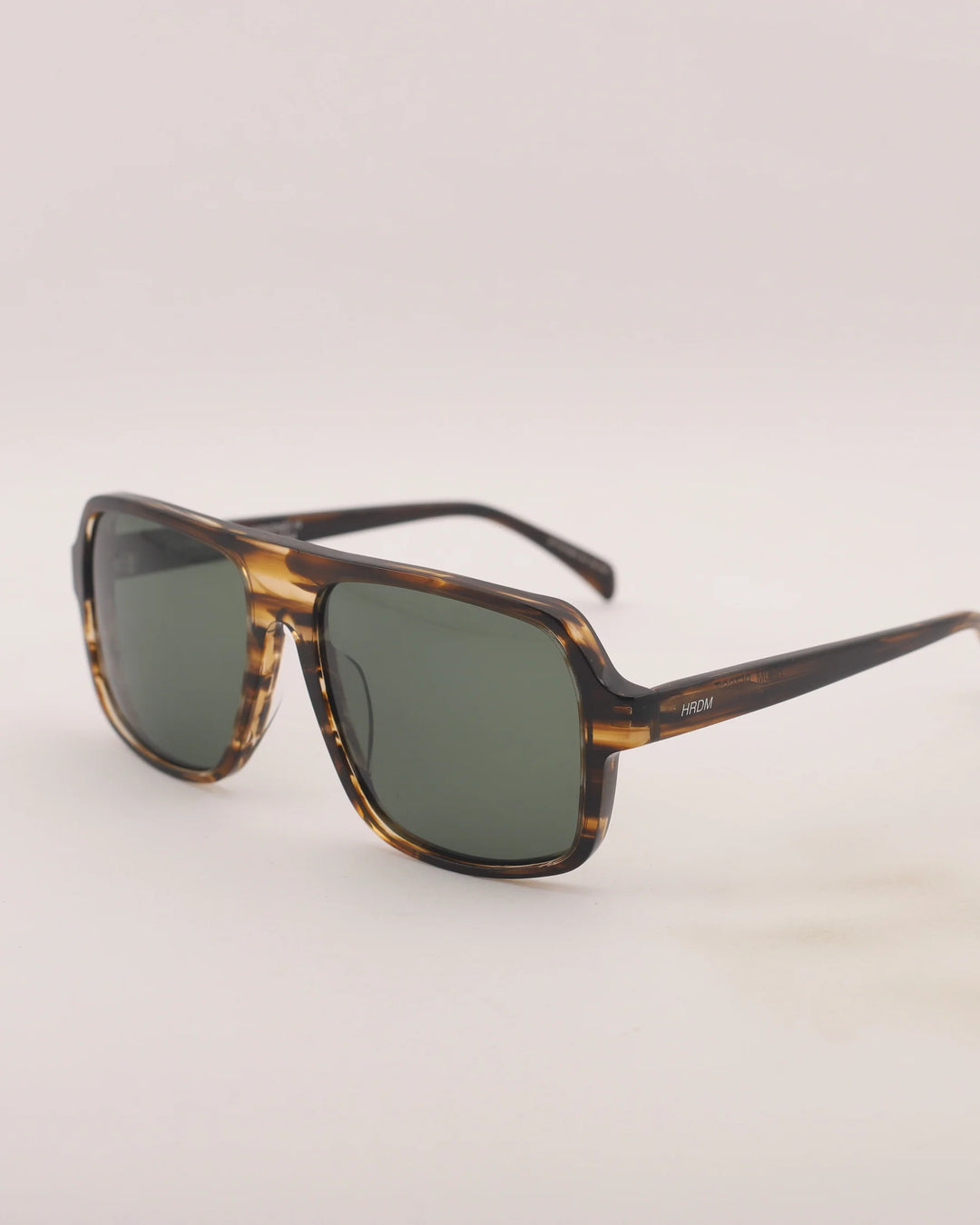Sunglasses with tortoiseshell frame and dark lenses on a light gray background