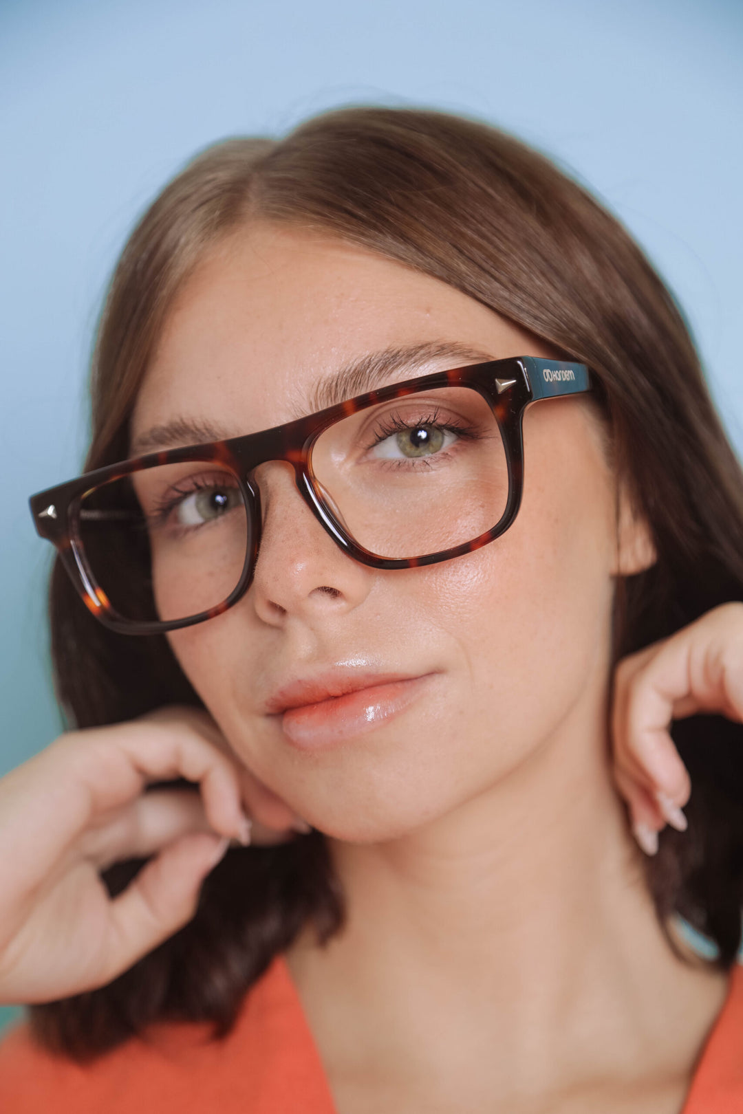 Person wearing a pair of glasses with a blue background