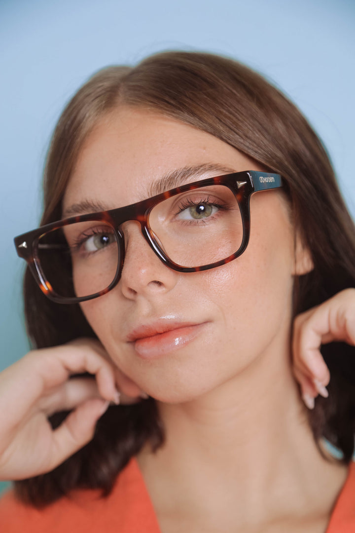 Person wearing a pair of glasses with a blue background