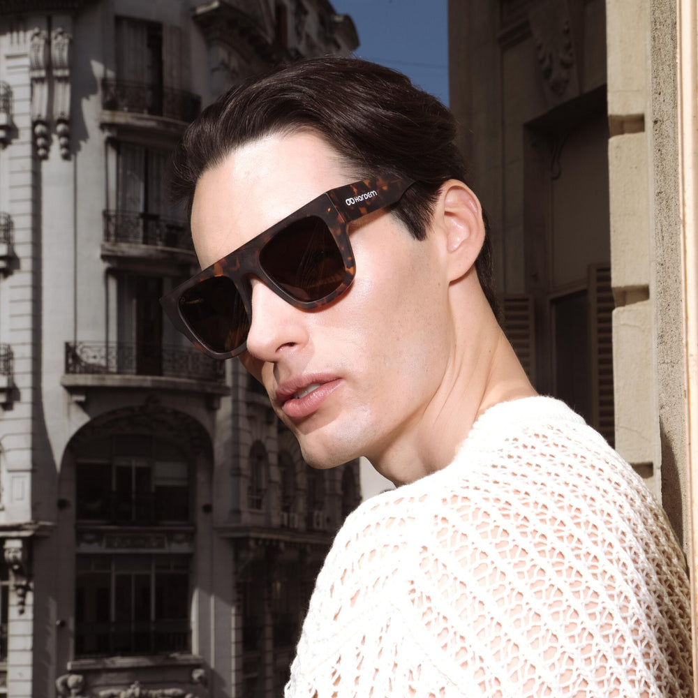 Francisco Villa wearing tortoiseshell sunglasses with a cityscape background