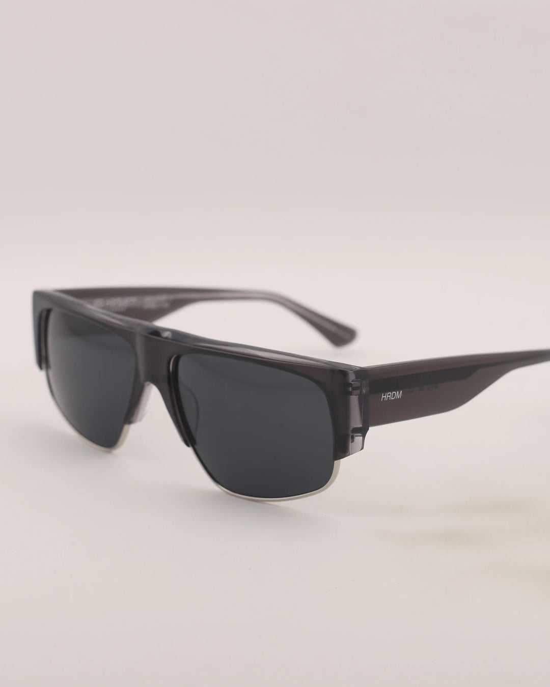 Sunglasses with dark lenses and thin frame on a light gray background