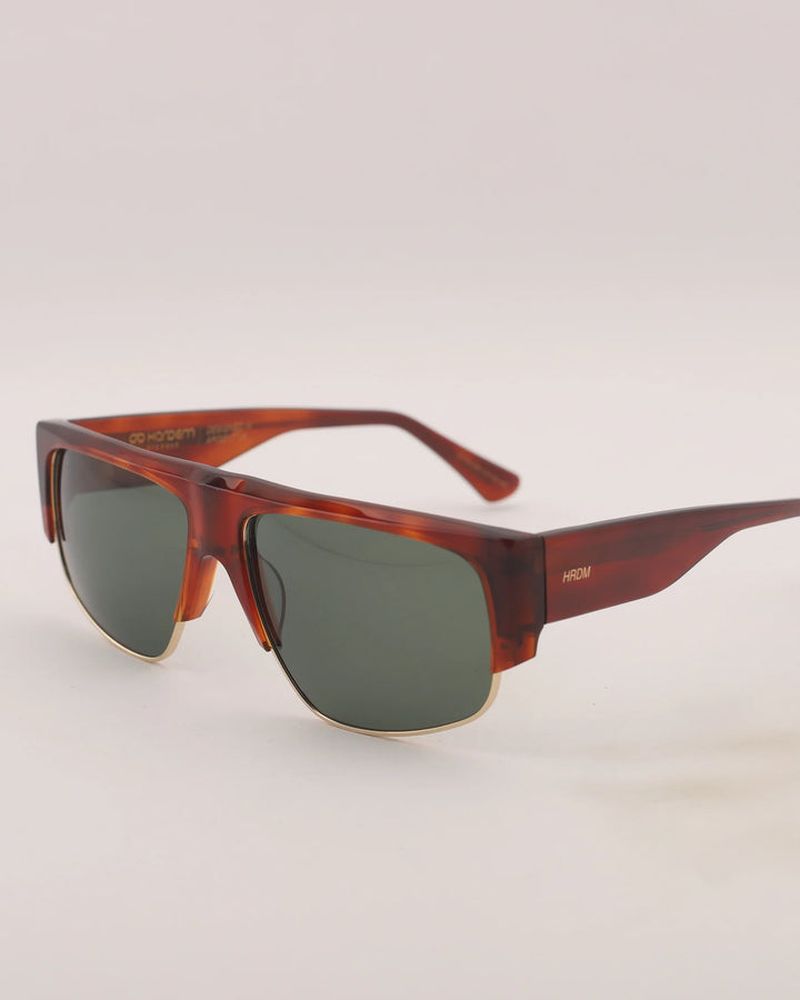 Sunglasses with tortoiseshell frame and dark lenses on a light gray background
