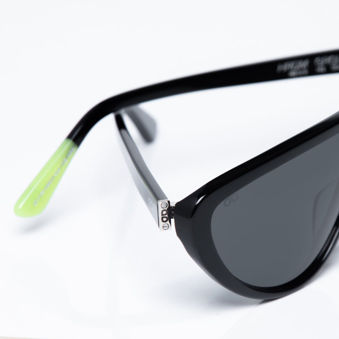 Black sunglasses with a green accent on a white background