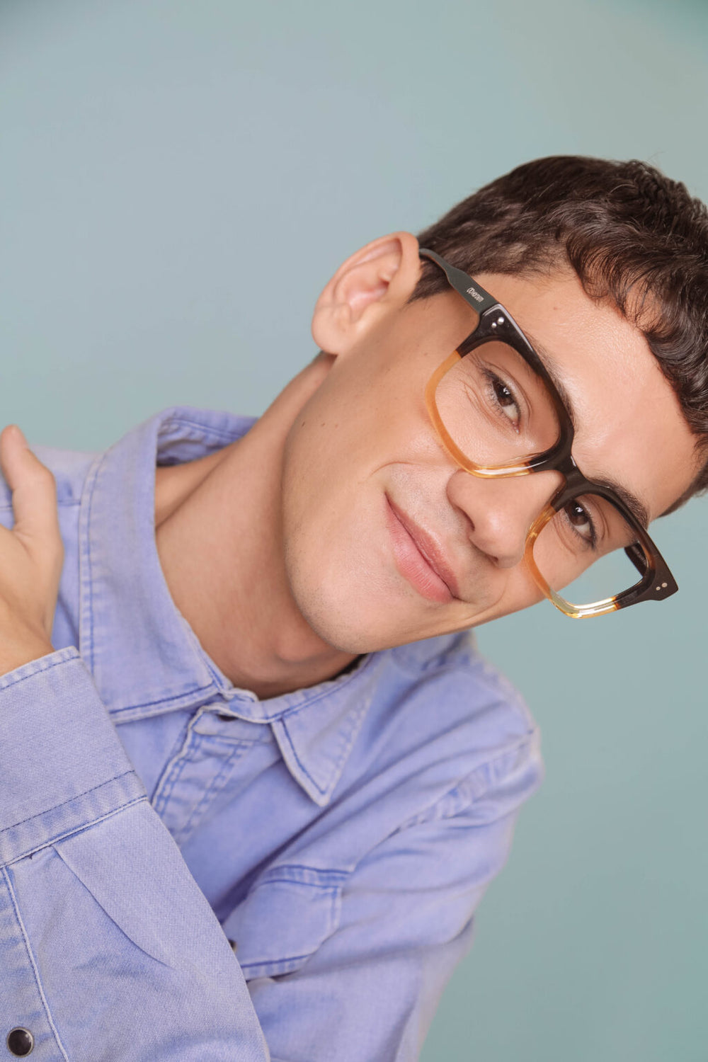 Person wearing glasses with a blue shirt against a light blue background