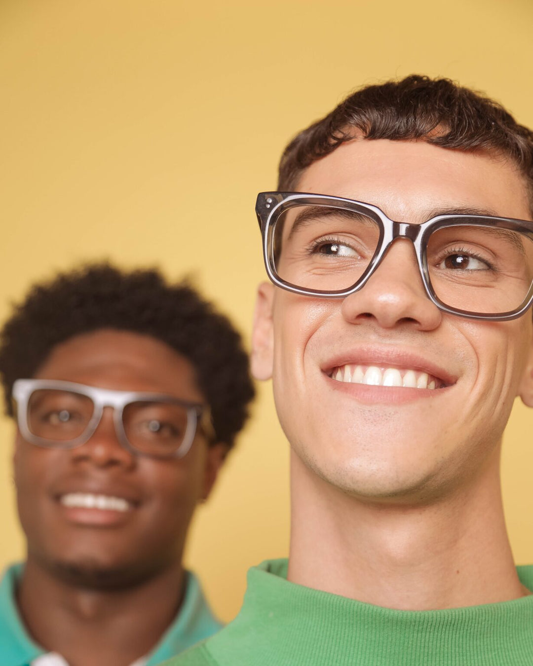 Two men wearing glasses with a yellow background