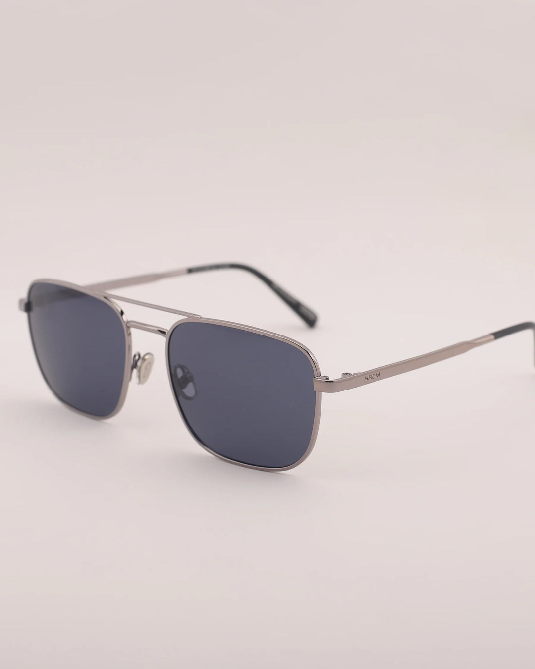 Sunglasses with dark lenses and thin metal frame on a light gray background
