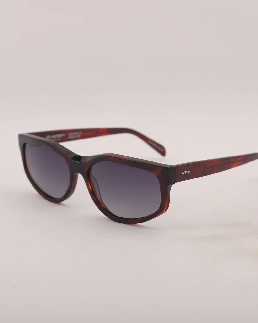 Sunglasses with tortoiseshell frame and dark lenses on a light gray background