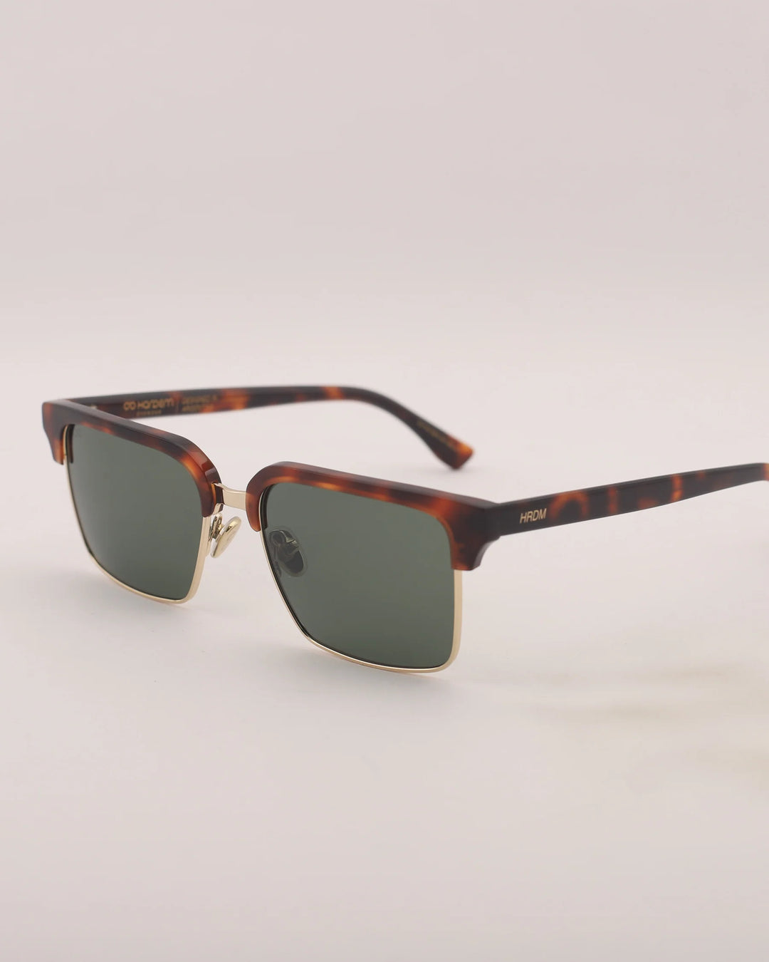Sunglasses with tortoiseshell frame and gold accents on a light gray background