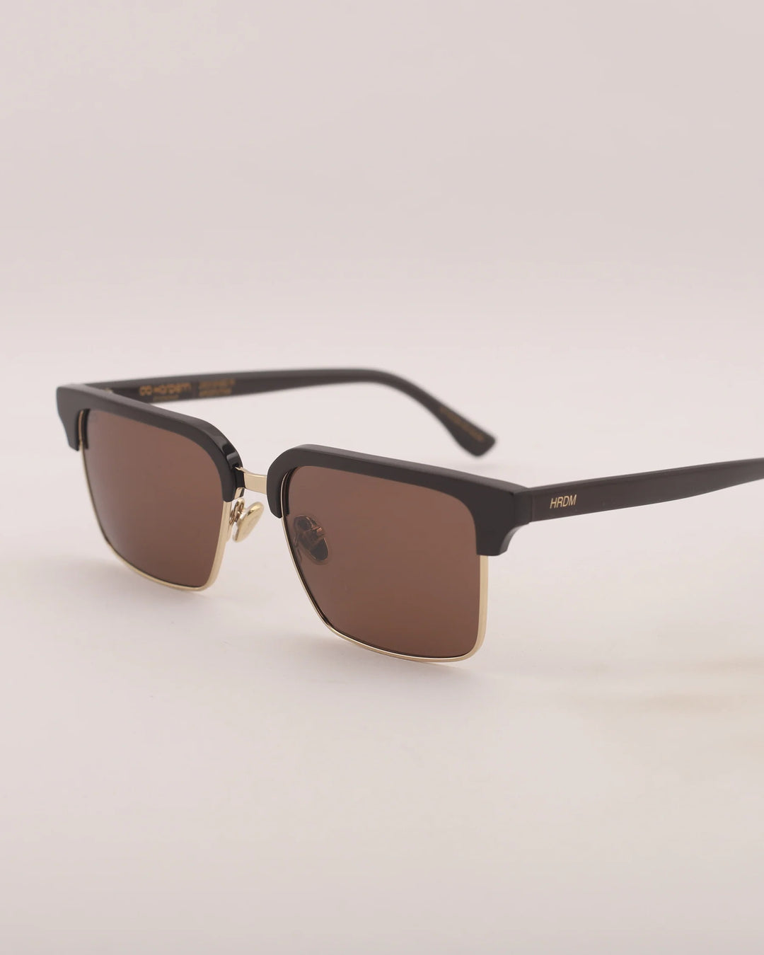 Black sunglasses with brown lenses on a light beige background