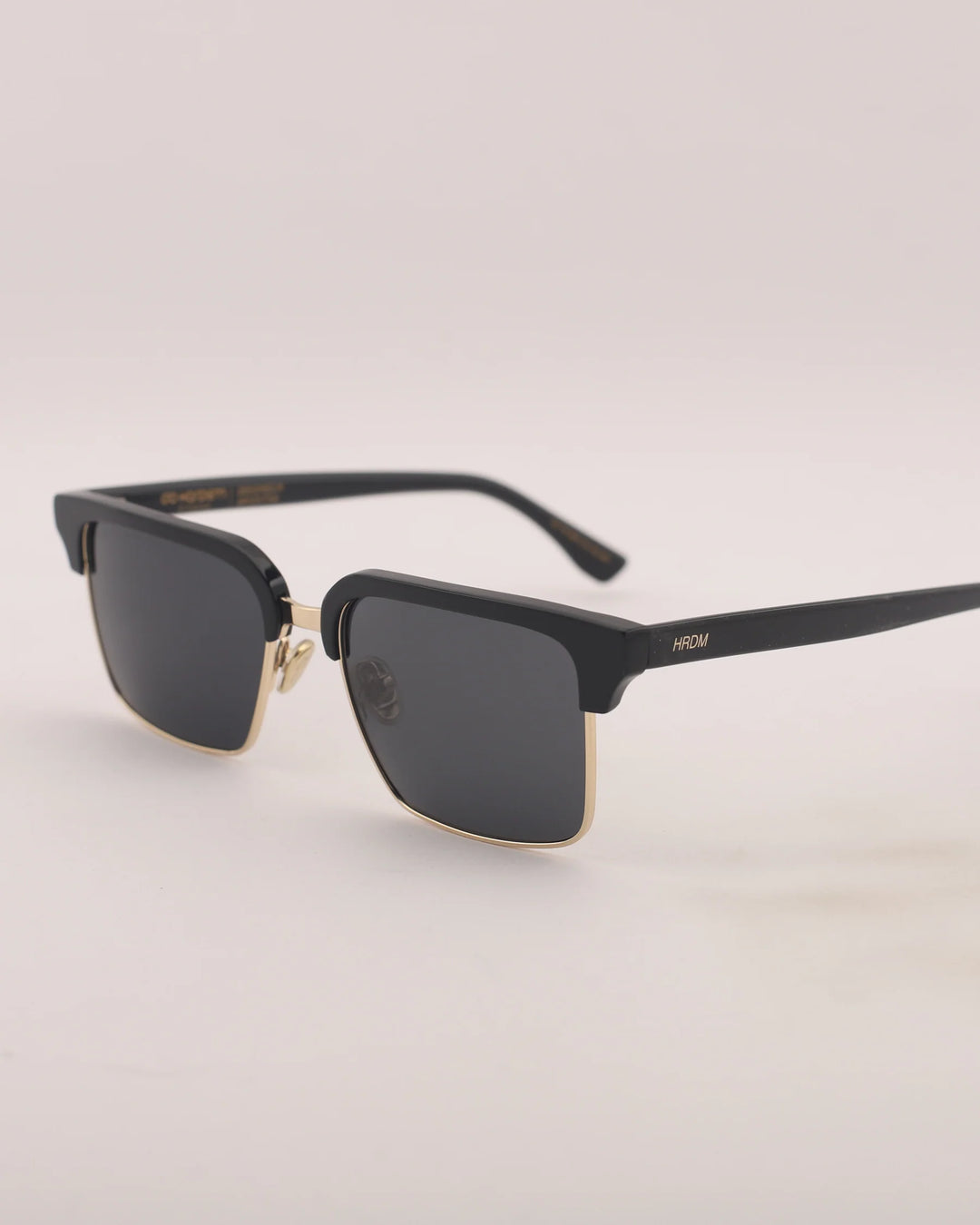 Black sunglasses with gold accents on a light gray background