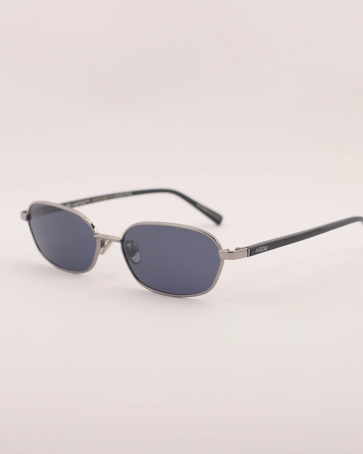 Sunglasses with a metallic frame and dark lenses on a light gray background
