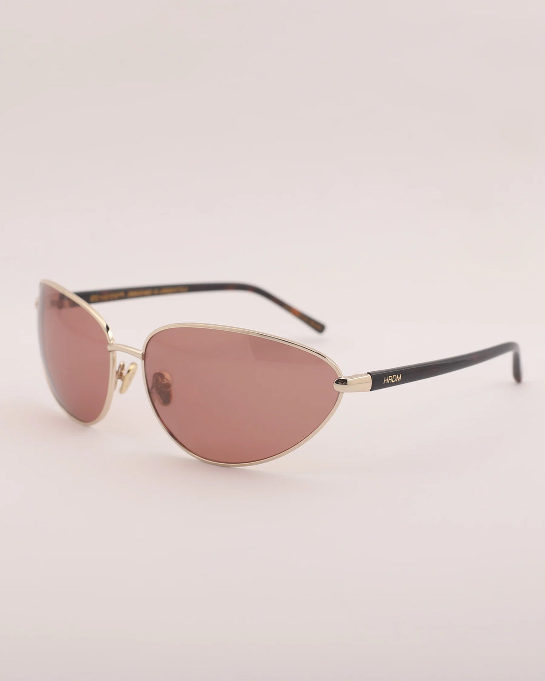 Sunglasses with gold frame and pink lenses on a light gray background
