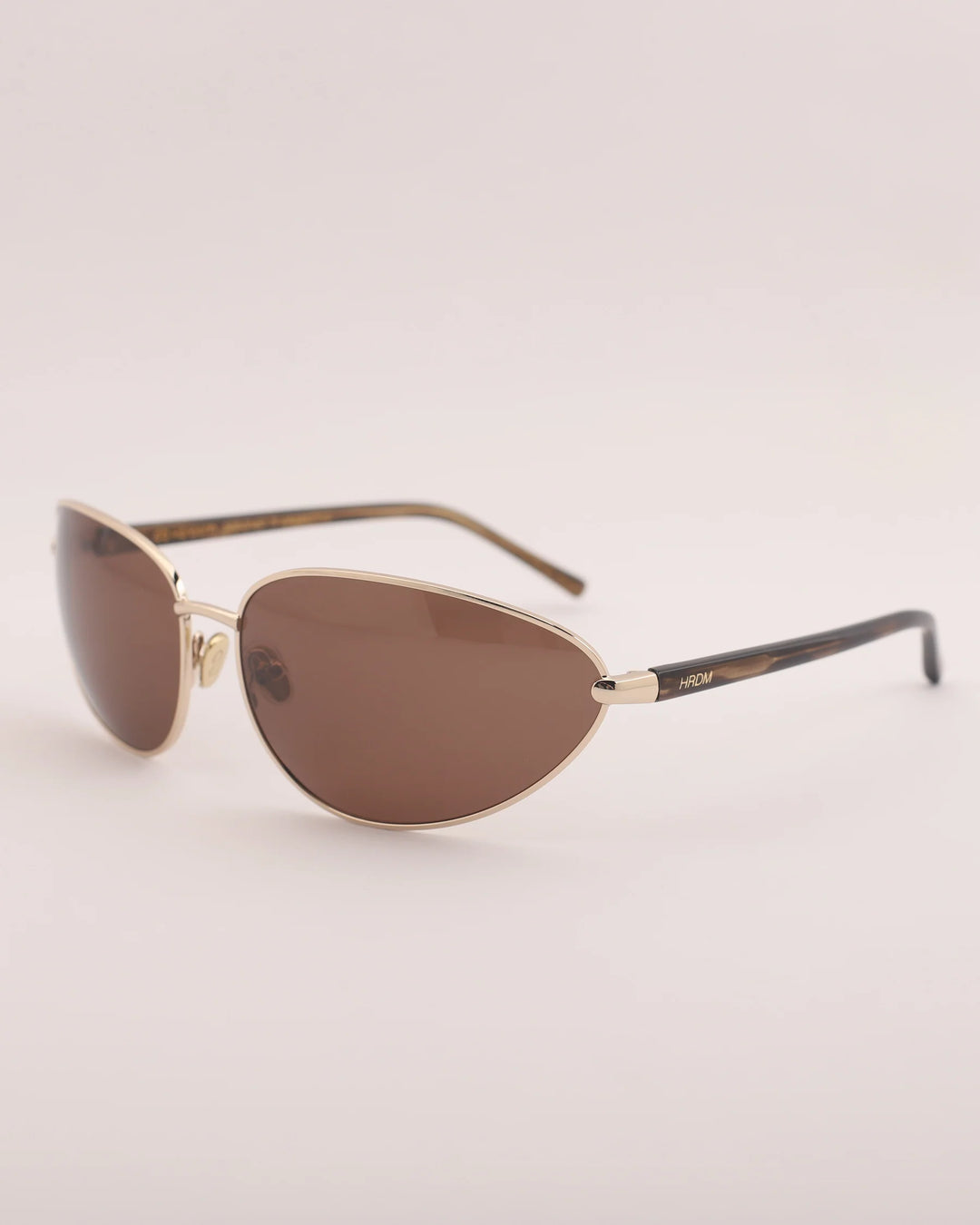 Sunglasses with gold frame and brown lenses on a light gray background