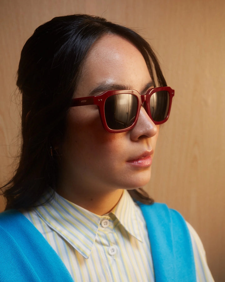 Person wearing red sunglasses with a neutral background