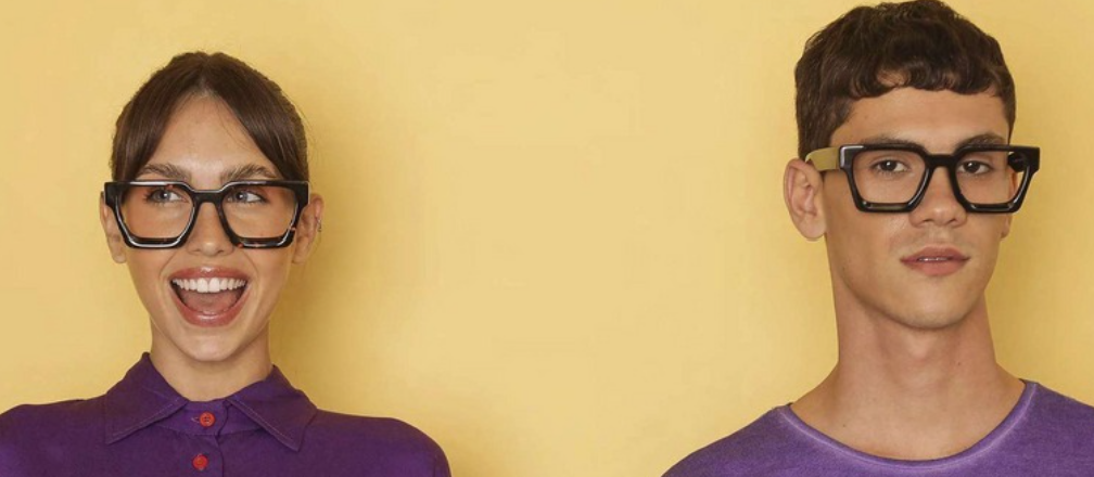 Two people wearing black glasses against a yellow background
