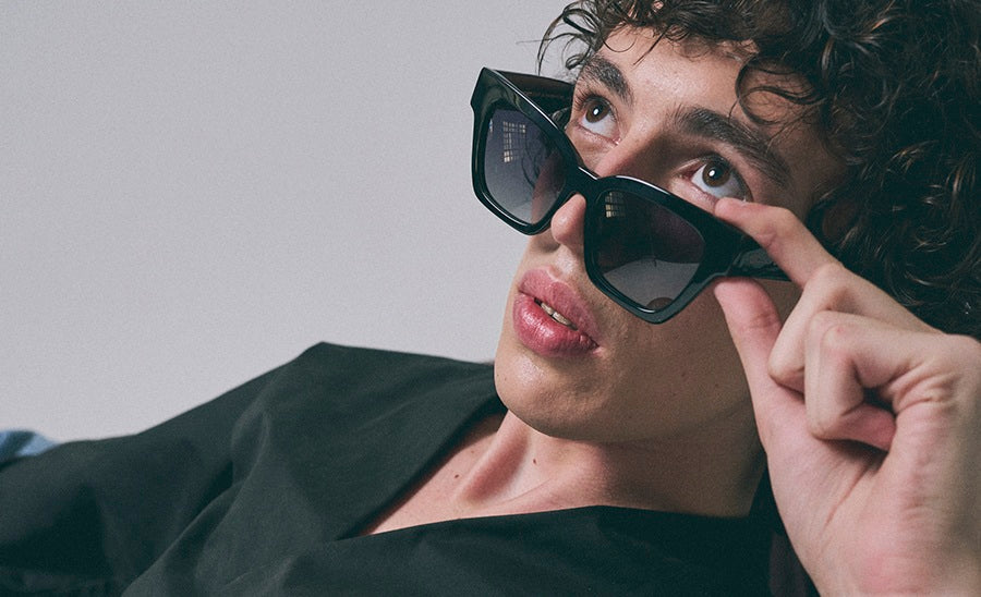 Person wearing large black sunglasses with a neutral background